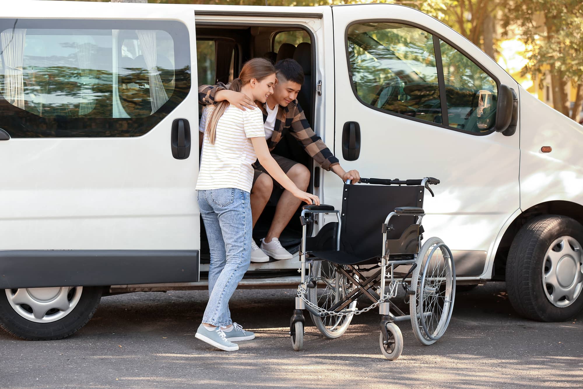 woman helping young man out of a van and into a wheelchair